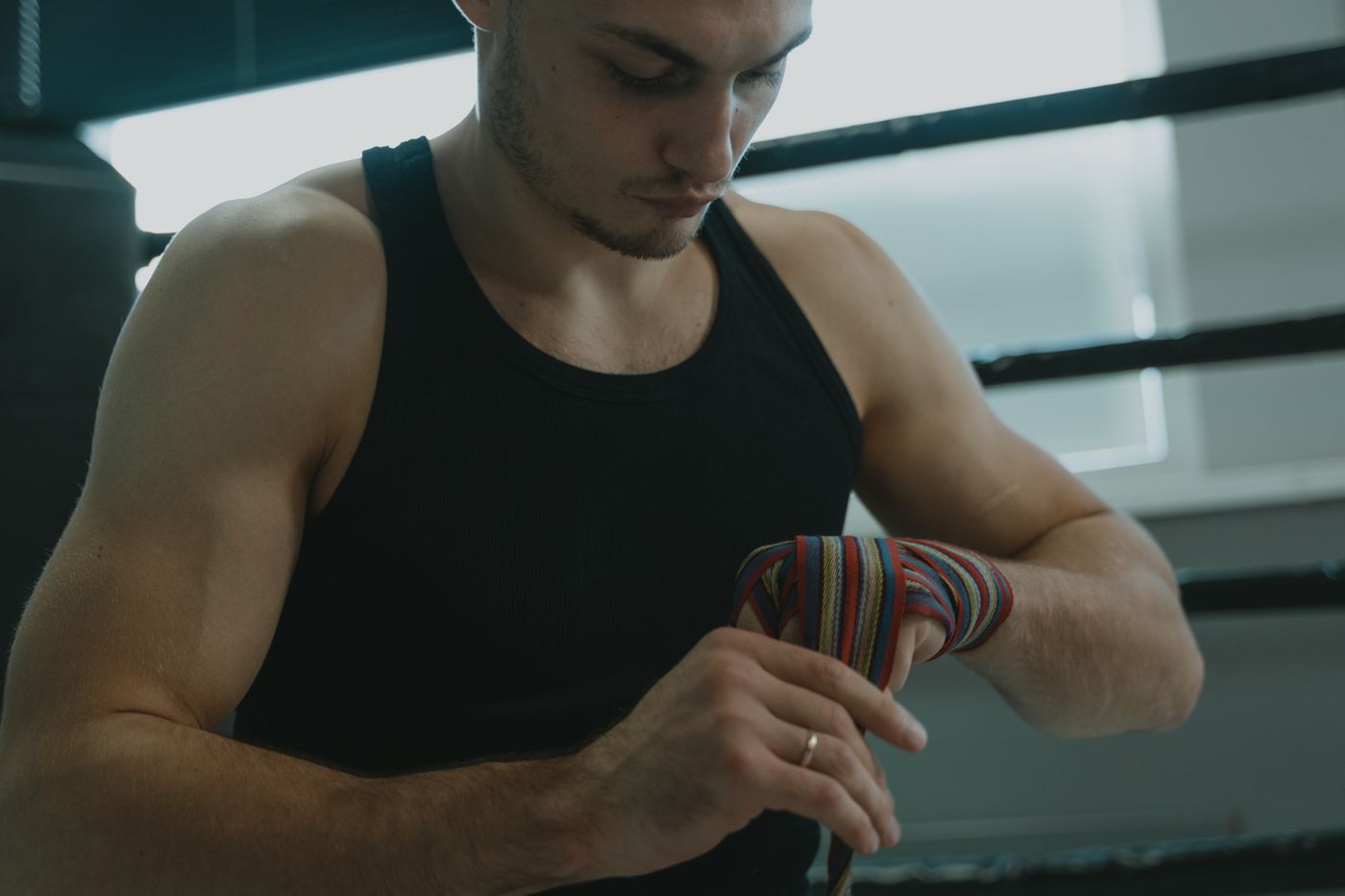 Een sporter wikkelt zijn handen in voor de training, naast de touwen van de ring.